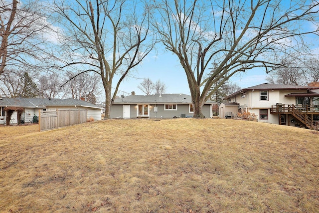 rear view of house featuring a lawn, a wooden deck, a chimney, and stairway