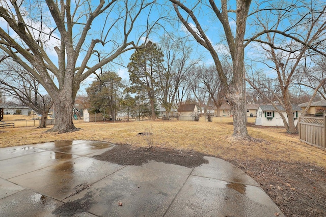 view of yard featuring a patio, fence, a residential view, and an outdoor structure