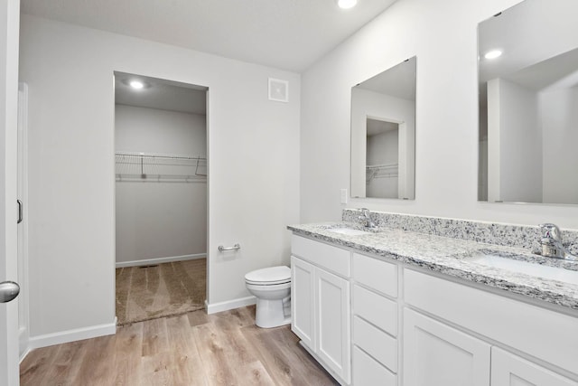 full bath featuring toilet, double vanity, visible vents, and a sink