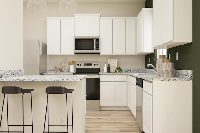 kitchen featuring a sink, white cabinets, a kitchen bar, and appliances with stainless steel finishes