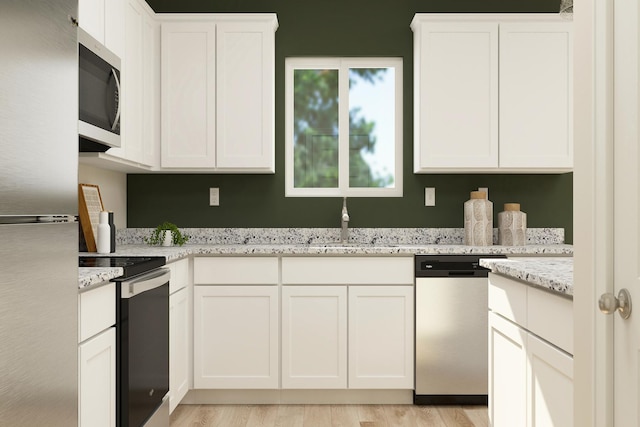 kitchen with white cabinetry, a sink, appliances with stainless steel finishes, and light wood-type flooring