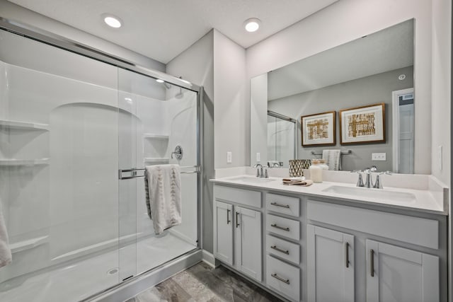 bathroom with double vanity, a stall shower, and a sink