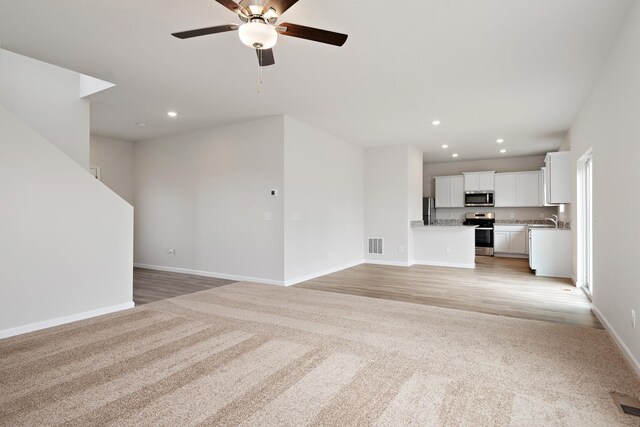 unfurnished living room with light carpet, baseboards, visible vents, and recessed lighting