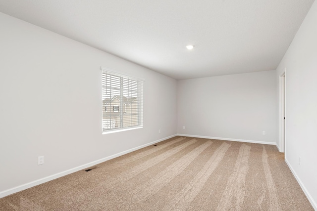 empty room featuring light carpet, visible vents, and baseboards