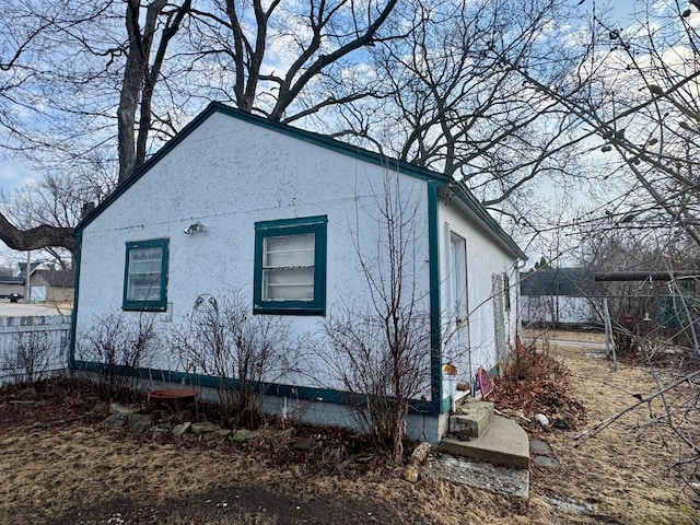 view of side of property with fence and stucco siding