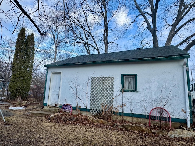 view of side of property with entry steps, roof with shingles, and stucco siding