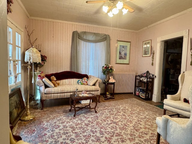 living area featuring radiator, a wealth of natural light, crown molding, and wood finished floors