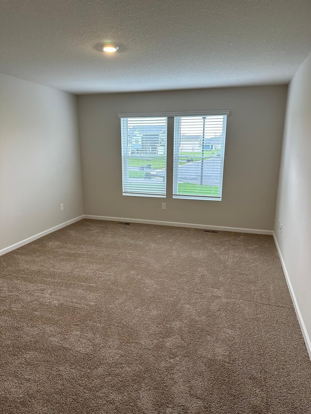 empty room featuring carpet flooring, a textured ceiling, and baseboards