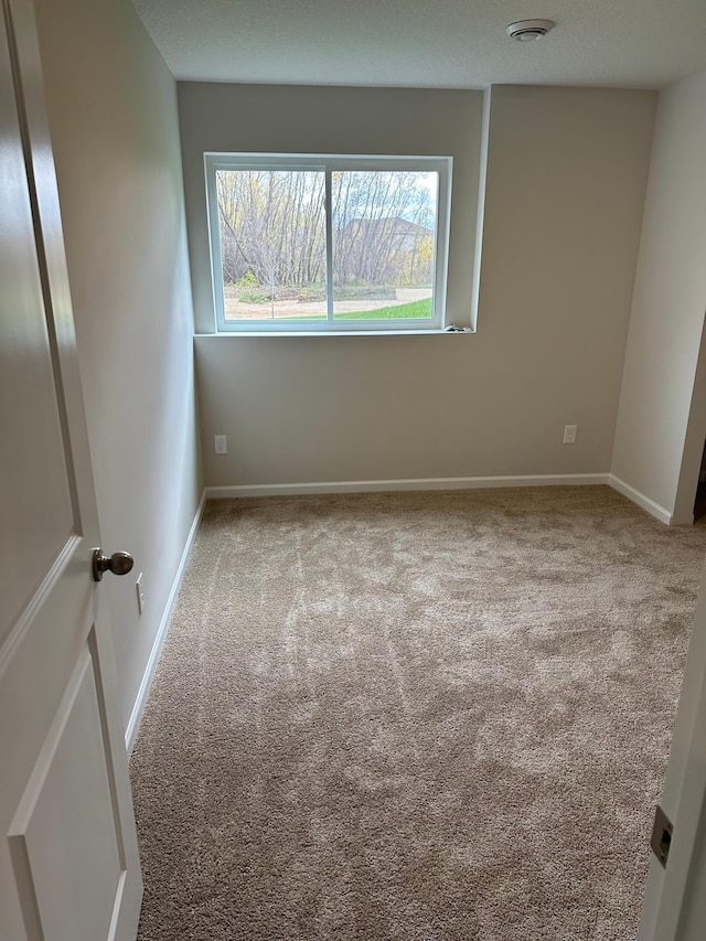 spare room with light carpet and baseboards