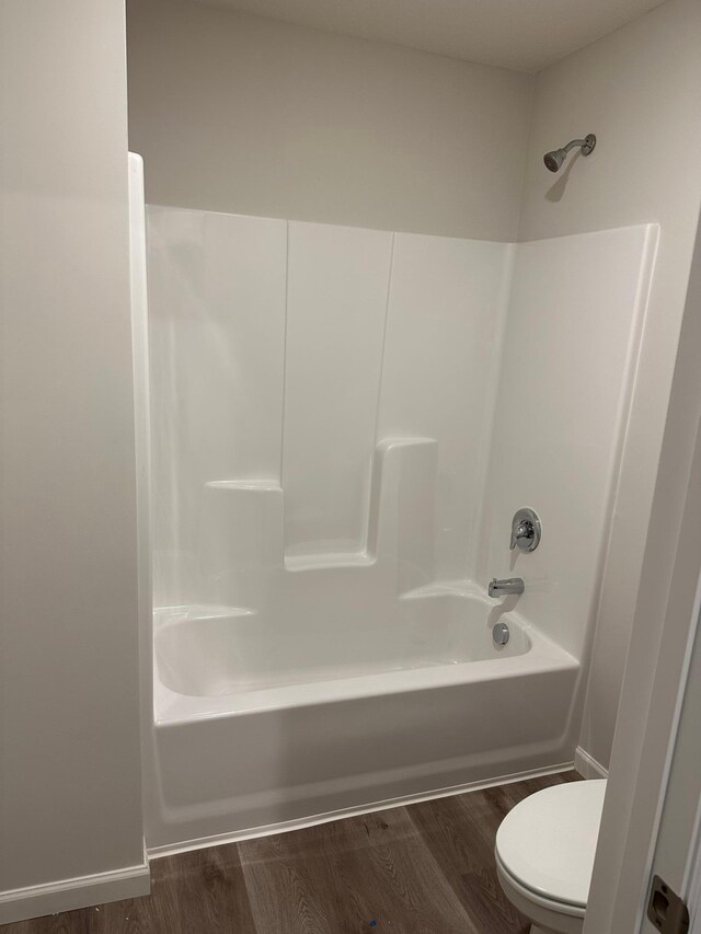 full bath featuring toilet, wood finished floors, and shower / bathtub combination