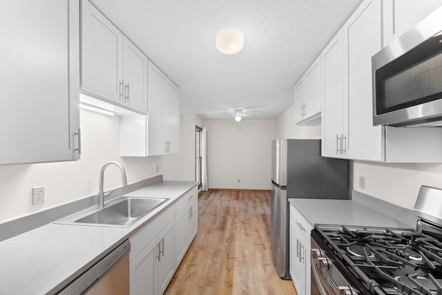 kitchen featuring light countertops, appliances with stainless steel finishes, white cabinetry, a sink, and ceiling fan