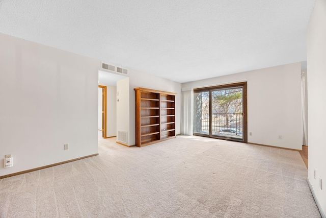 spare room with baseboards, visible vents, a textured ceiling, and carpet flooring