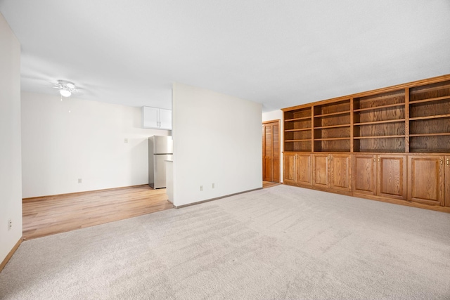 unfurnished living room with light carpet, ceiling fan, and baseboards