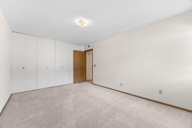 unfurnished bedroom with carpet floors, a closet, visible vents, a textured ceiling, and baseboards