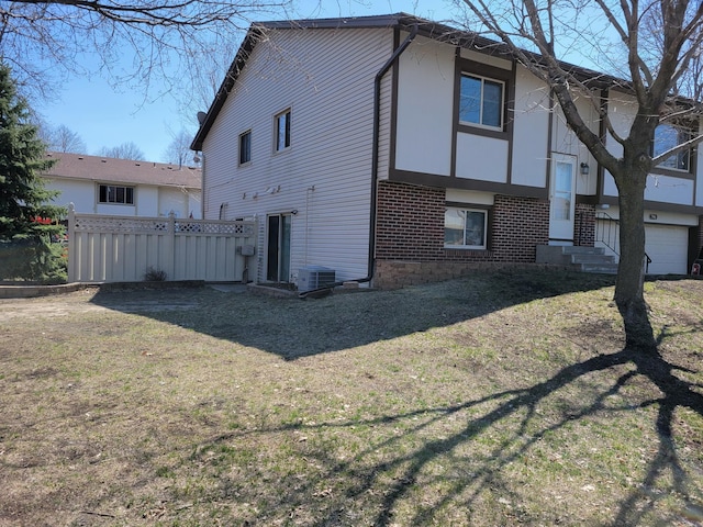 view of property exterior with brick siding, fence, central AC, and a lawn