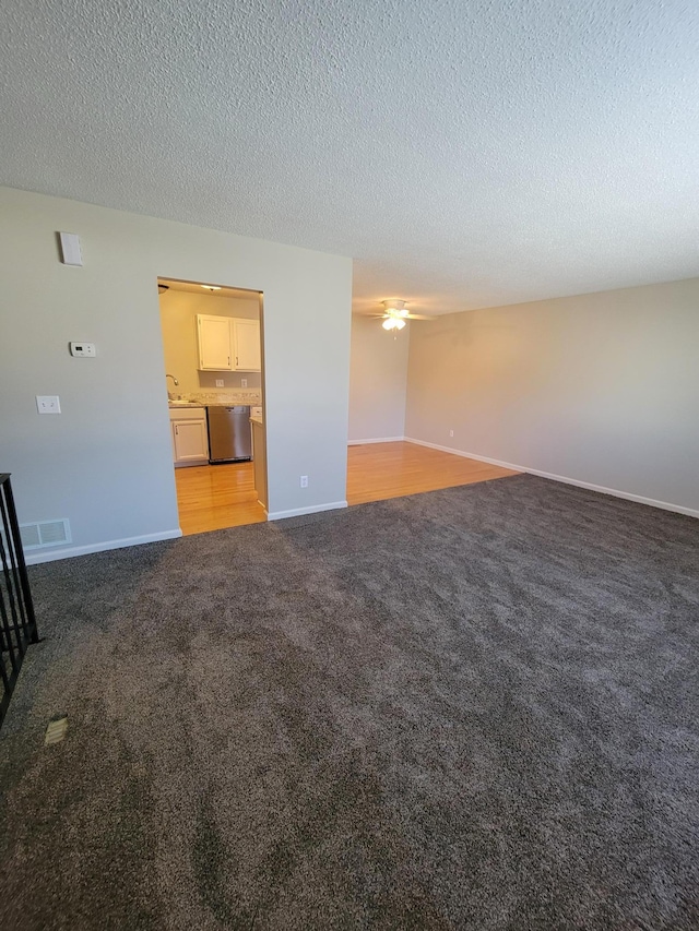 unfurnished living room with light carpet, baseboards, visible vents, a textured ceiling, and a sink