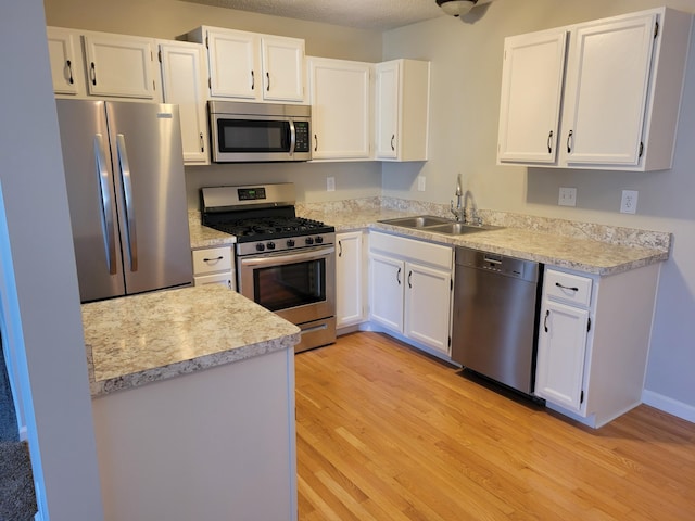 kitchen with light countertops, appliances with stainless steel finishes, light wood-type flooring, and a sink