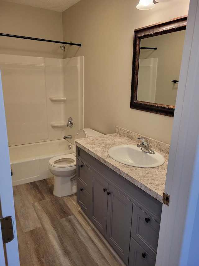 full bath with shower / washtub combination, vanity, toilet, and wood finished floors