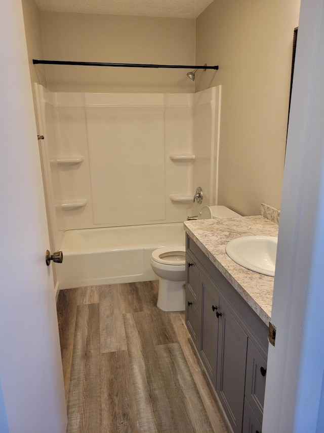 bathroom with toilet, washtub / shower combination, wood finished floors, and vanity