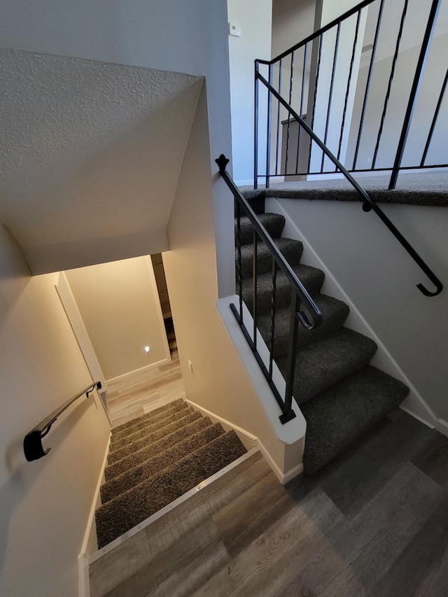 staircase with wood finished floors and baseboards