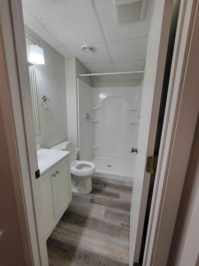 full bathroom with visible vents, toilet, vanity, a shower stall, and wood finished floors