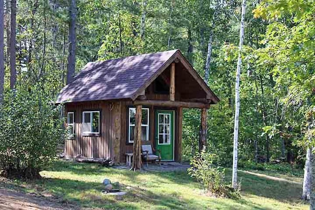 view of outdoor structure with a view of trees and an outbuilding