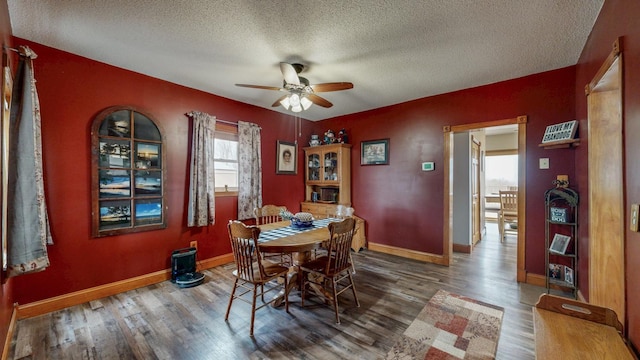 dining area with a ceiling fan, a textured ceiling, baseboards, and wood finished floors