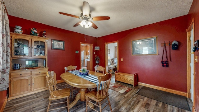 dining space featuring dark wood-style floors, ceiling fan, a textured ceiling, and baseboards