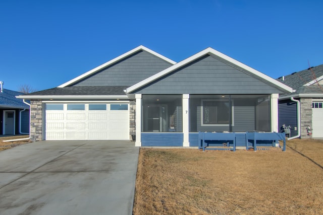 view of front facade with an attached garage, stone siding, a front lawn, and concrete driveway