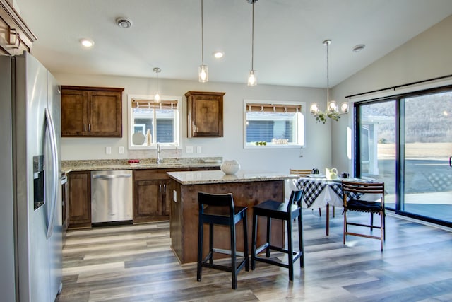 kitchen with stainless steel appliances, pendant lighting, a kitchen island, and a sink