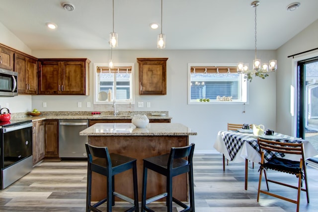 kitchen with hanging light fixtures, a kitchen island, stainless steel appliances, and a sink