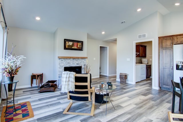 living area with washer / clothes dryer, visible vents, a fireplace, and light wood-style flooring