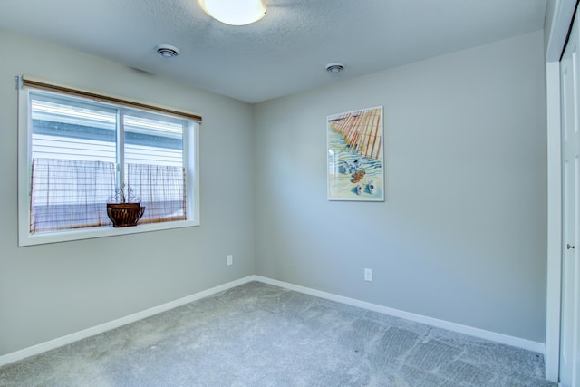 carpeted empty room featuring visible vents, baseboards, and a textured ceiling