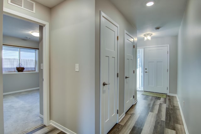 hall featuring wood finished floors, visible vents, and baseboards