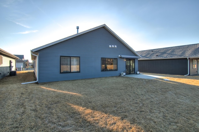 rear view of house featuring central AC unit, a lawn, and a patio area