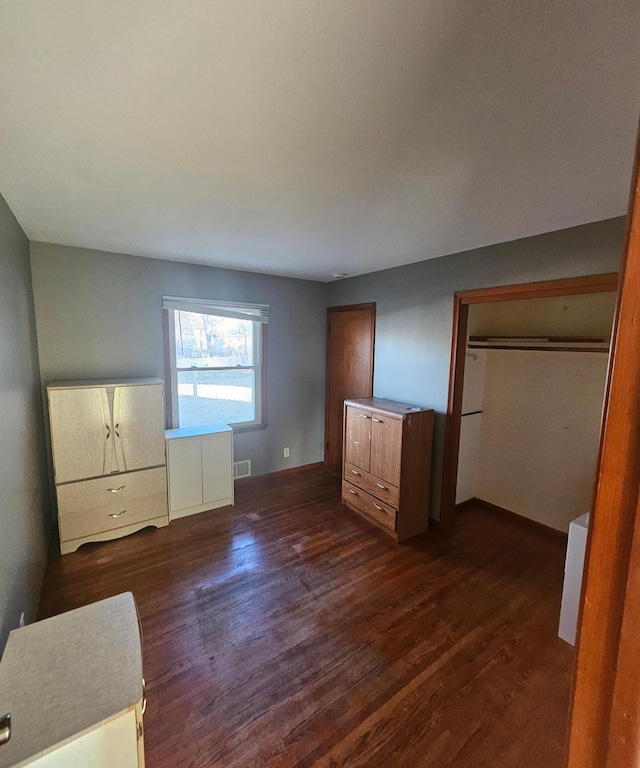 unfurnished bedroom featuring visible vents and dark wood finished floors