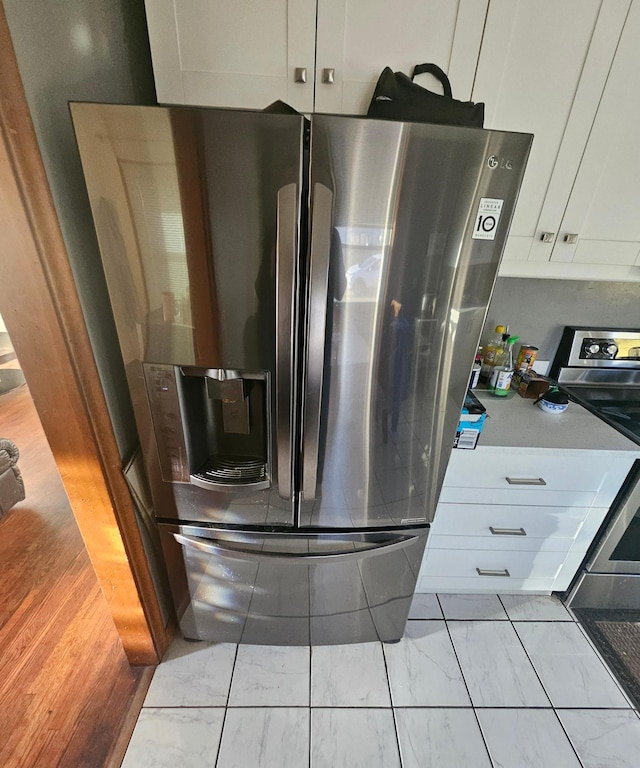 kitchen with marble finish floor, stainless steel refrigerator with ice dispenser, and white cabinetry