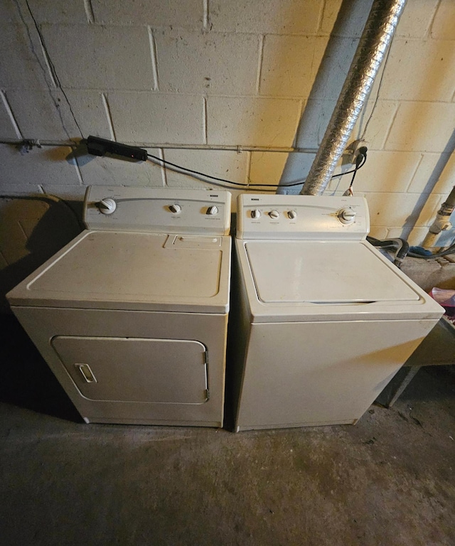 laundry room with laundry area, concrete block wall, and washer and dryer