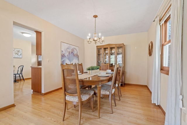 dining room with a chandelier, light wood-style flooring, and baseboards