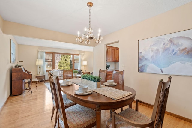 dining area with baseboards, light wood finished floors, and a chandelier