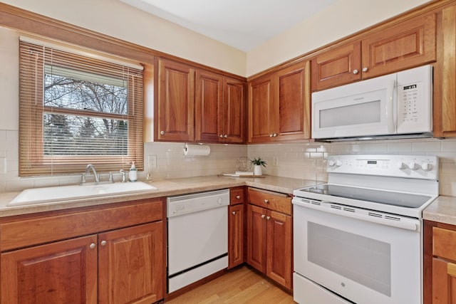 kitchen with tasteful backsplash, white appliances, light countertops, and a sink