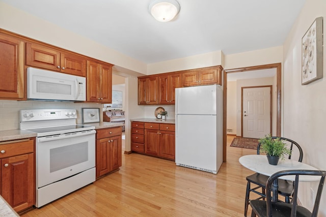 kitchen featuring light wood finished floors, brown cabinets, white appliances, and light countertops