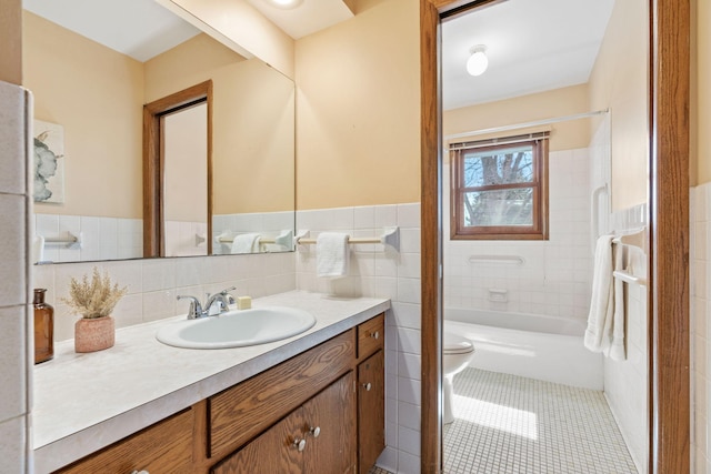 bathroom featuring vanity, tile patterned flooring, wainscoting, tile walls, and toilet