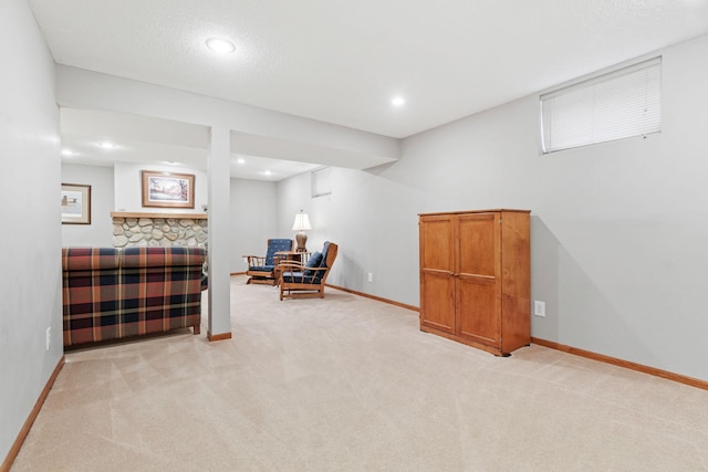 sitting room with a stone fireplace, recessed lighting, baseboards, and light carpet