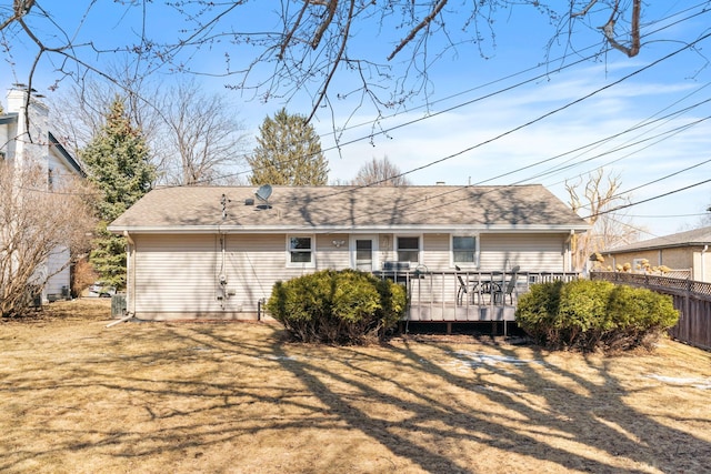 back of property featuring a deck, fence, and roof with shingles