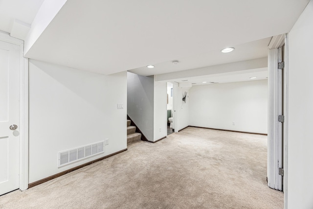 finished below grade area featuring baseboards, visible vents, stairway, and carpet flooring