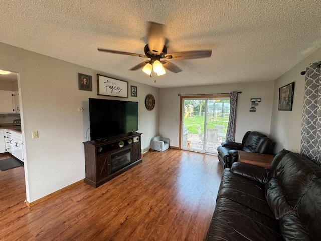 living room with baseboards, a textured ceiling, a ceiling fan, and wood finished floors