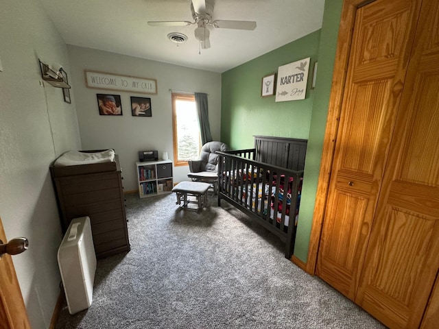 carpeted bedroom featuring ceiling fan, a crib, and visible vents