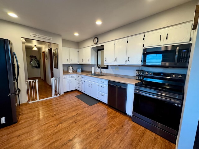 kitchen featuring wood finished floors, a sink, white cabinetry, light countertops, and appliances with stainless steel finishes