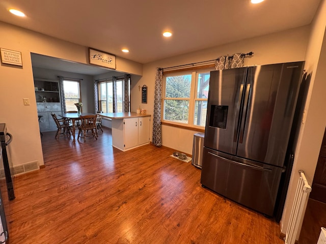 kitchen featuring recessed lighting, visible vents, wood finished floors, a peninsula, and stainless steel fridge with ice dispenser